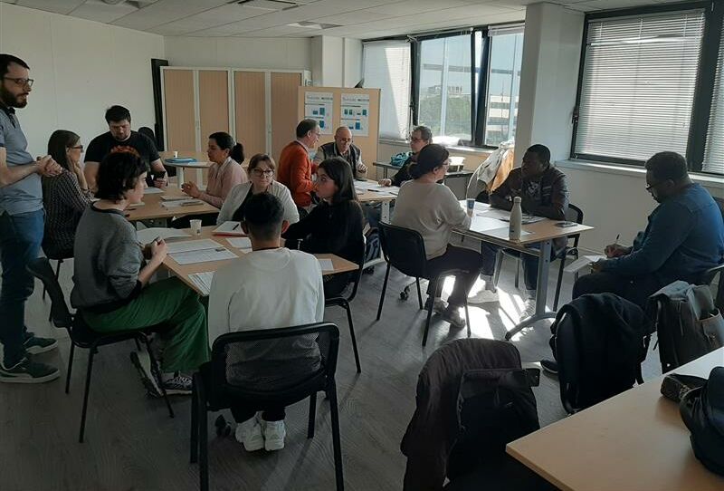 Groupe de personnes assis autours de table et qui travaille